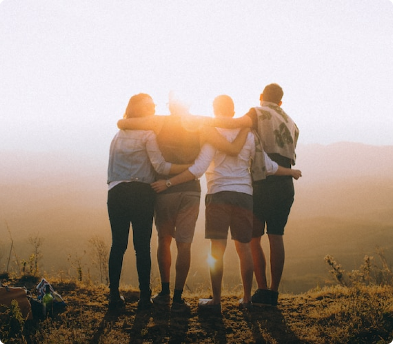 Four people hugging looking towards sunset