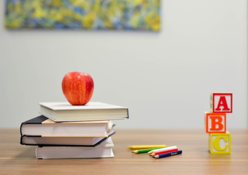 Books on a desk with an apple