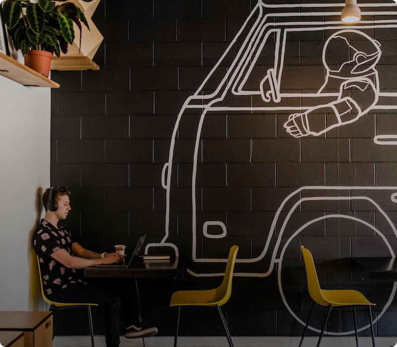 Man working along at table in cafe on laptop