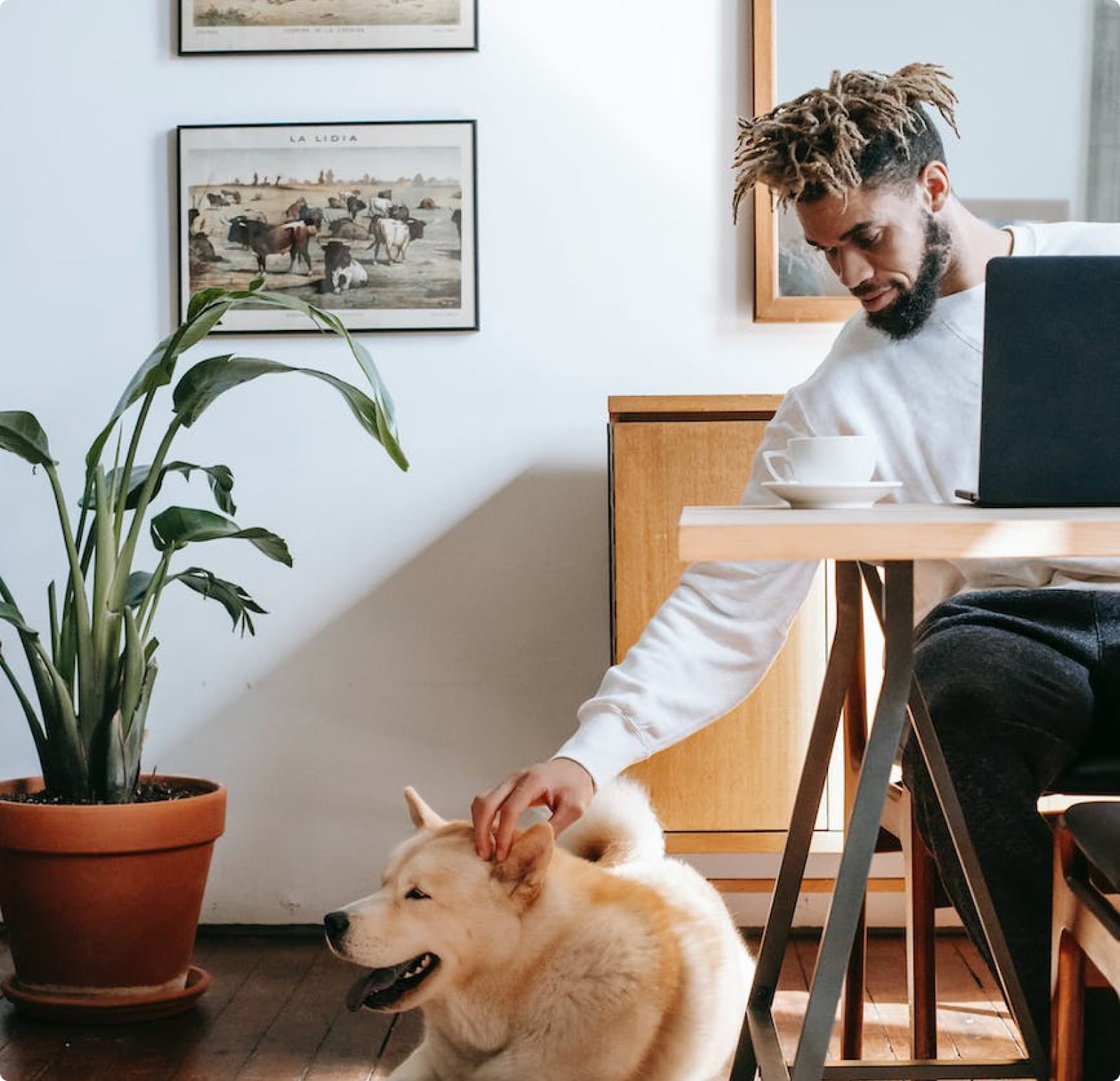 Man petting his dog while at work sitting at desk.